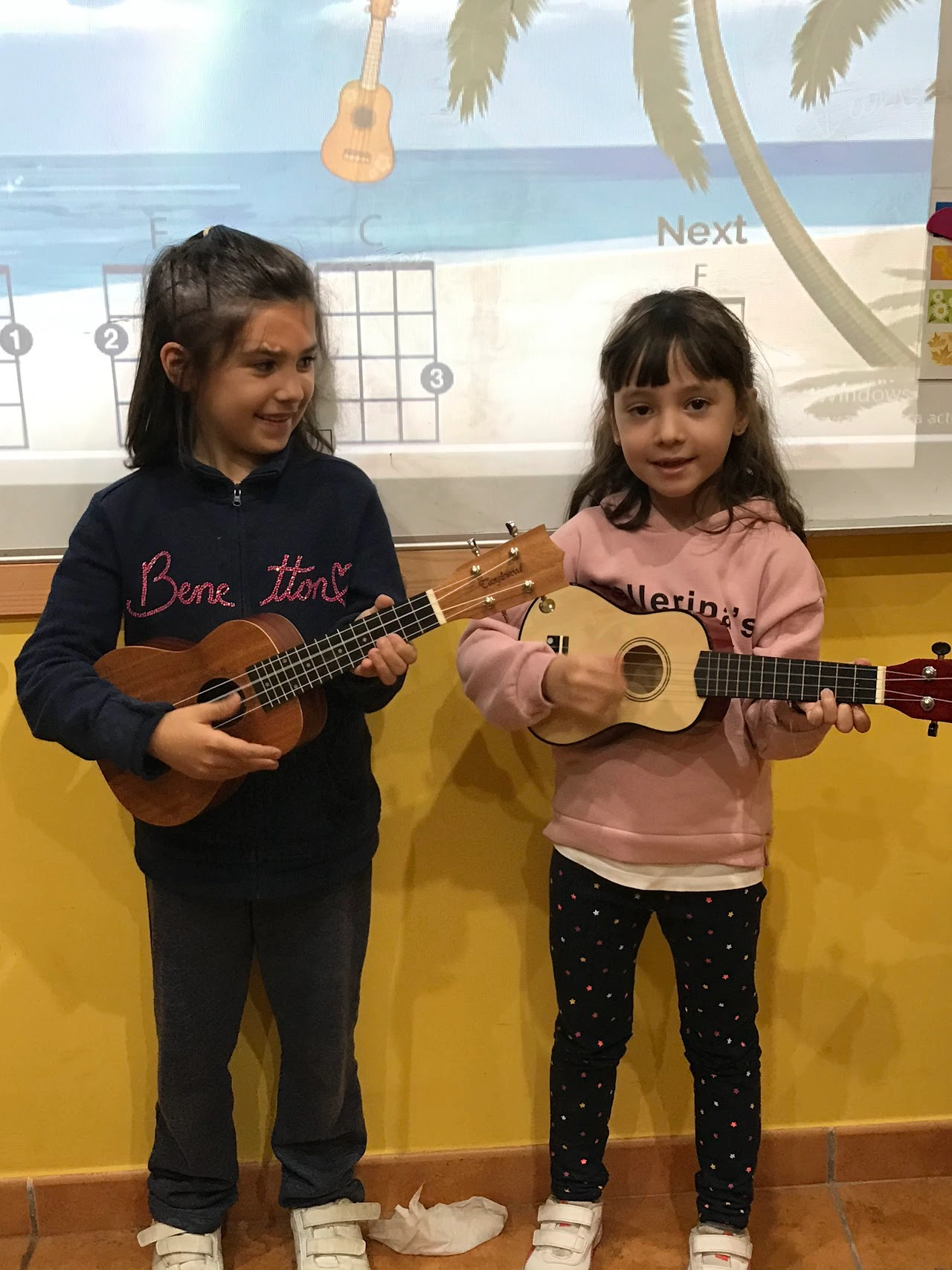 Dos alumnas de la academia de inglés tocando mini guitarras