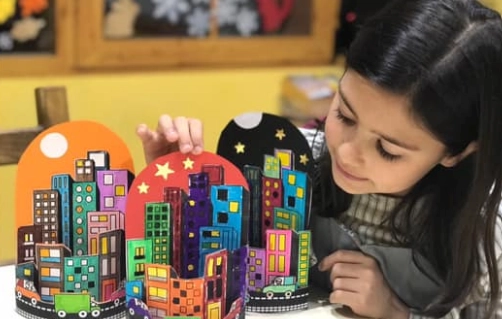 Alumna sonriente con maqueta de una ciudad